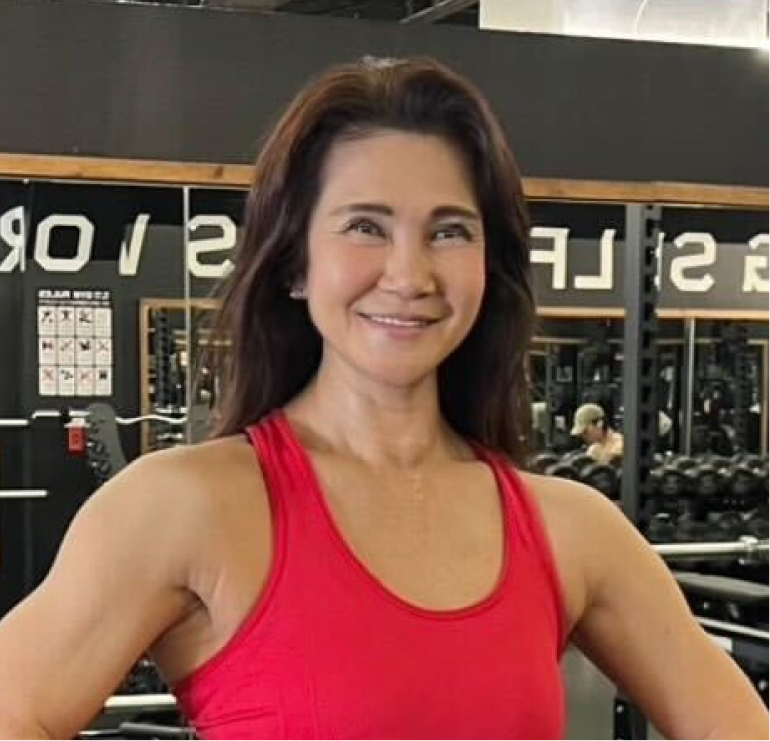 フィットネスジムで赤いタンクトップを着て笑顔でポーズを取る女性